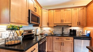 Una cucina con mobili in legno, un frigorifero in acciaio inossidabile, un forno a microonde e una macchina per il caffè.