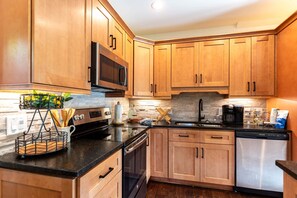 A kitchen with wooden cabinets, a stainless steel refrigerator, a microwave, and a coffee maker. - Moonlight View at Eagles Nest River Club, 2,000 feet of private fishing streams, hot tub! (Banner Elk)