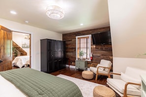 Quarto com cama, guarda-roupa, televisão e parede de madeira.