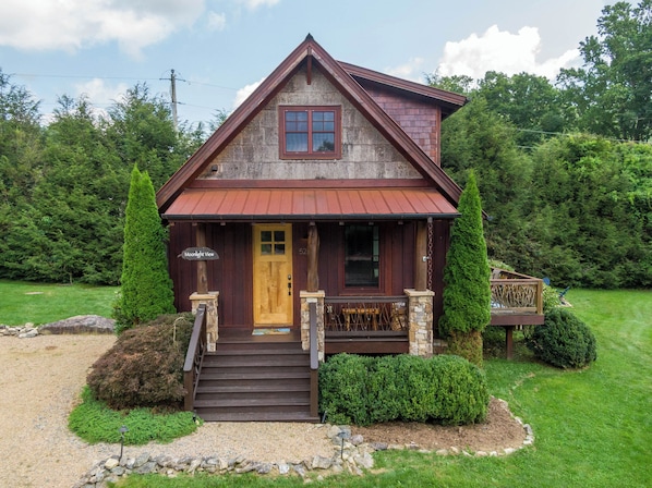 A wooden cabin with a front porch, a wooden door, and a small set of stairs leading to the entrance.