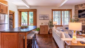 Una cucina moderna con isola centrale, mobili in legno e zona pranzo con divano e tavolo.