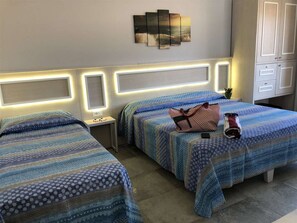A hotel room with two beds, a bedside table, a nightstand, a wall-mounted artwork, and a wardrobe. - B&B Holiday Tropea (Tropea)