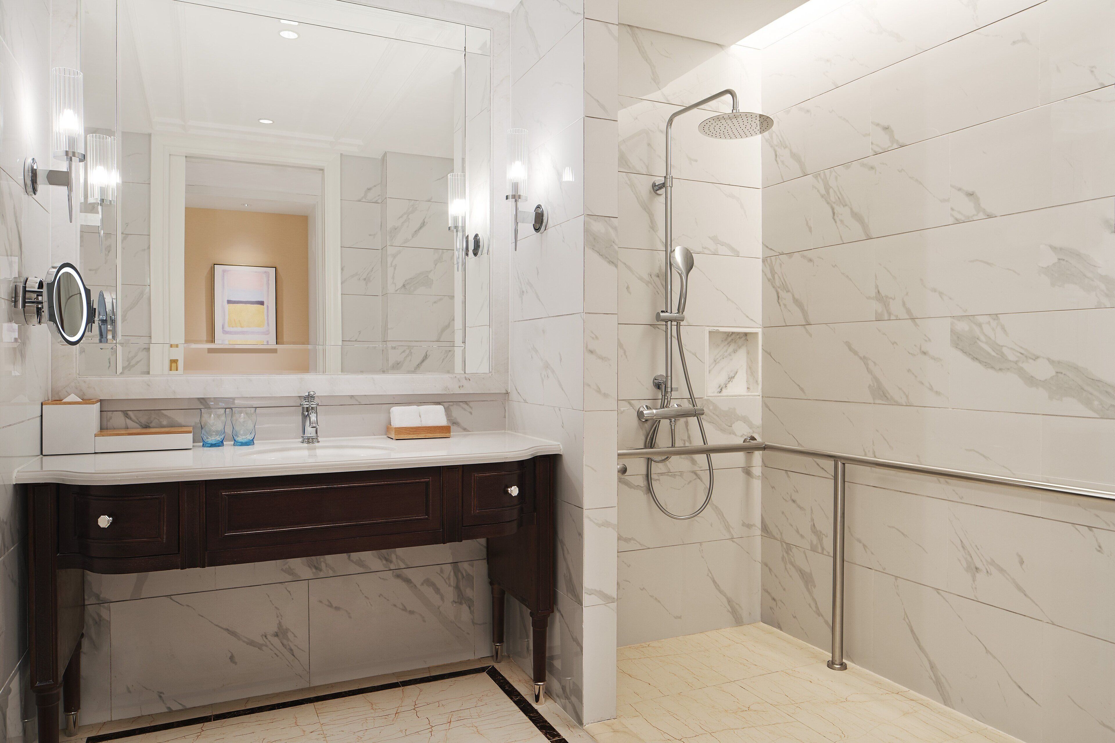 A modern bathroom with a marble vanity, a large mirror, and a walk-in shower with a glass door.