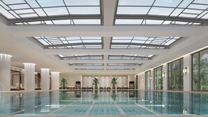 A spacious indoor swimming pool with a high ceiling and skylights, surrounded by seating areas and large windows. - Sheraton Yinchuan (Yinchuan)