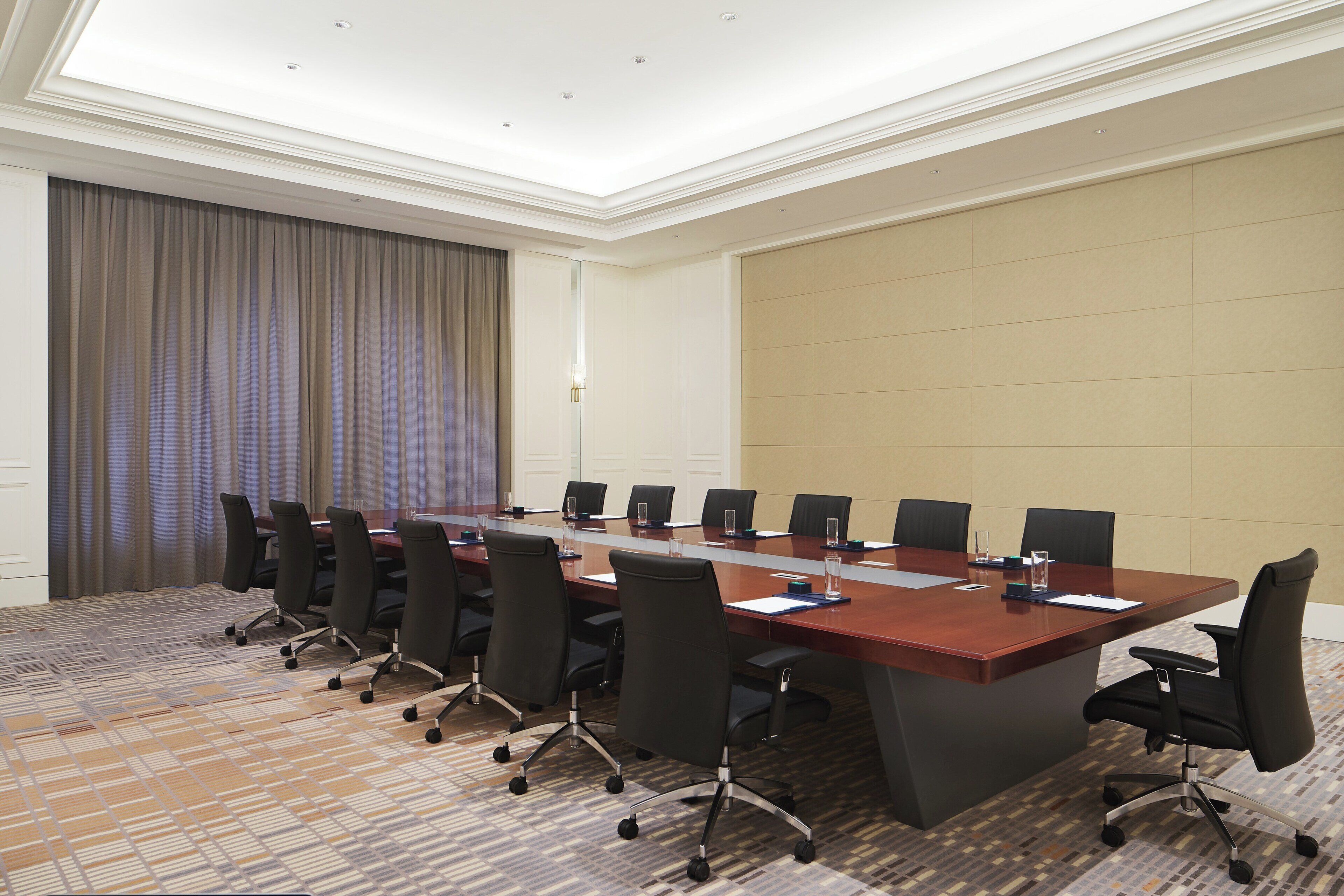 Un salón de conferencias con una larga mesa, varias sillas y suelo alfombrado.