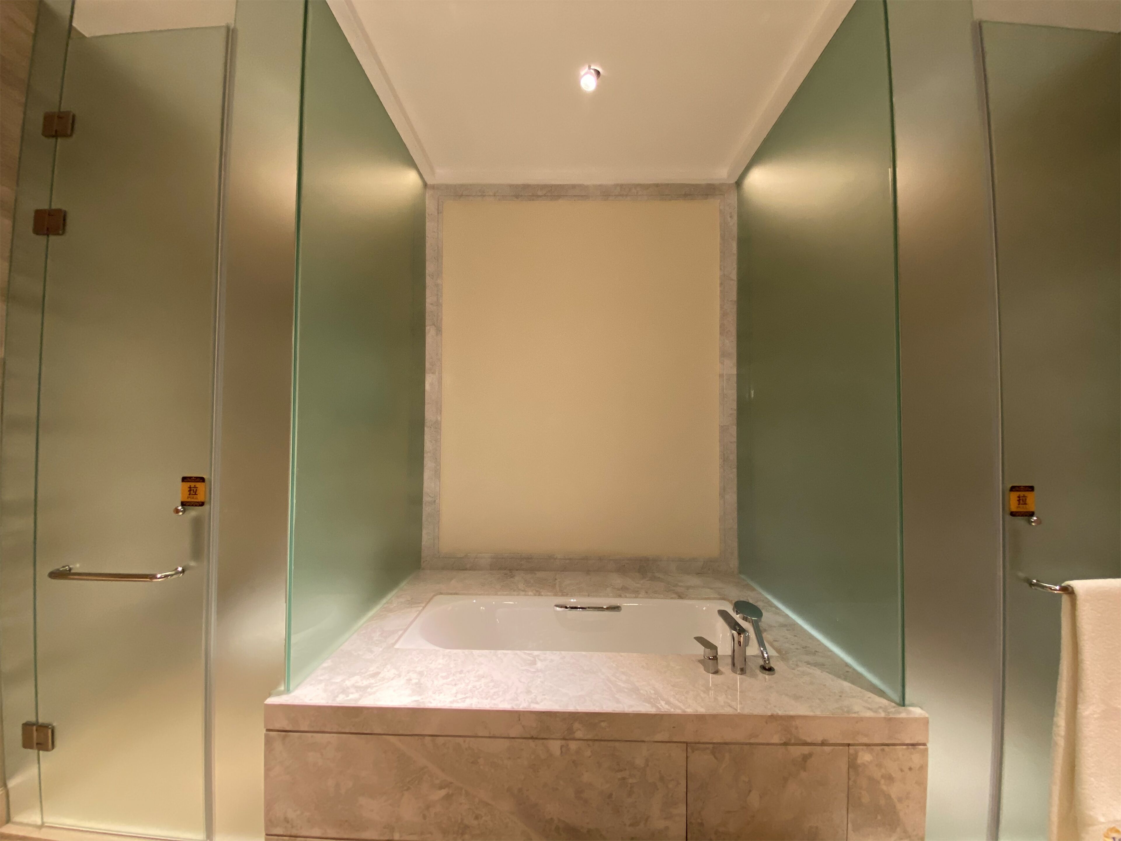 Een moderne badkamer met een douchecabine van glas, een ruime badkuip en een marmeren wastafelblad.