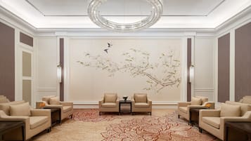 A spacious room with a large chandelier, two sofas, a small table, and a decorative wall mural.