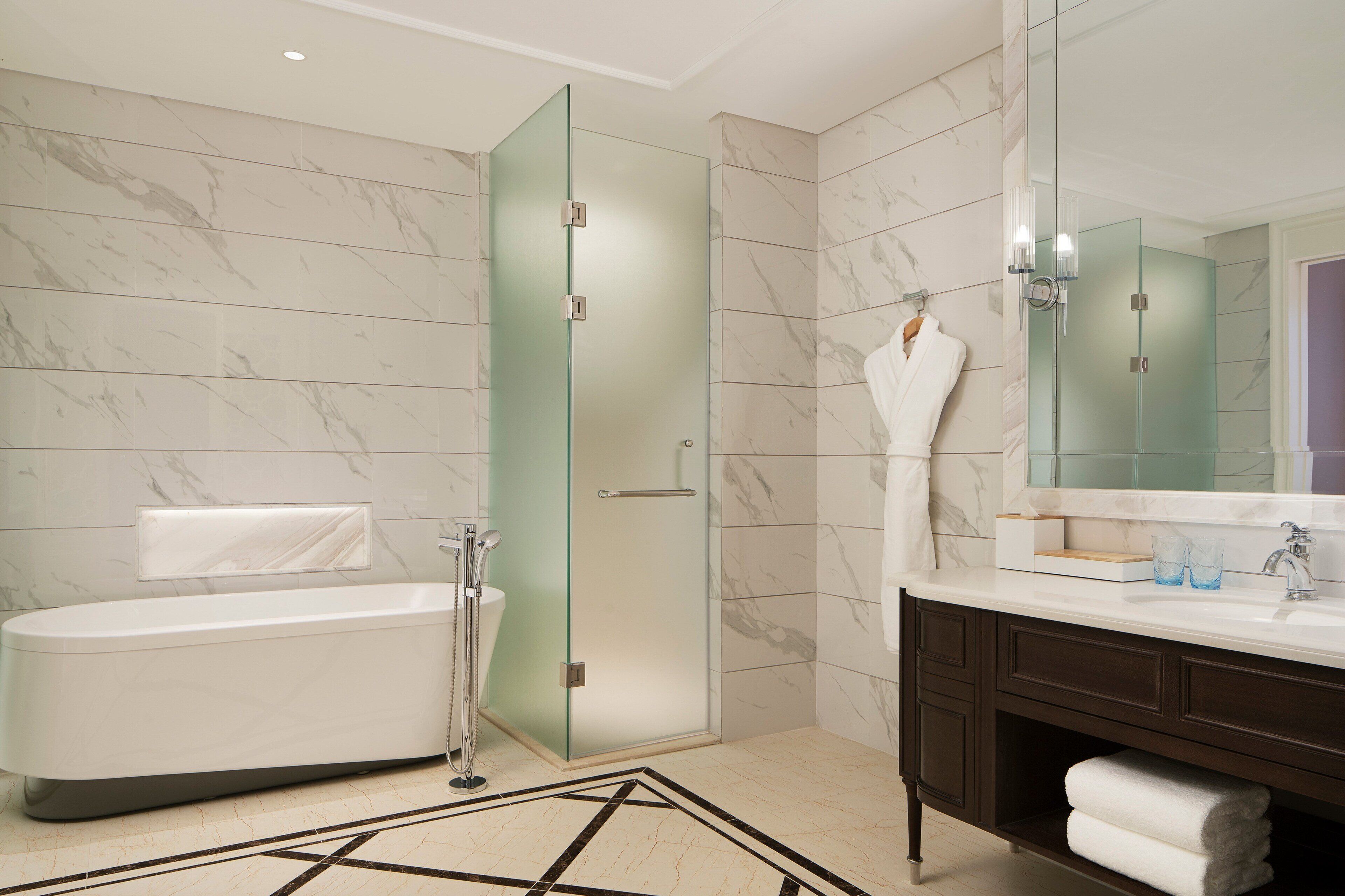 Une salle de bain moderne dotée d’une douche à parois de verre, d’une baignoire sur pieds et d’un meuble-lavabo en bois foncé agrémenté d’un grand miroir.