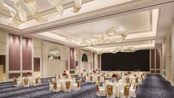 Un salón de banquetes con mesas redondas, manteles blancos y cintas doradas.