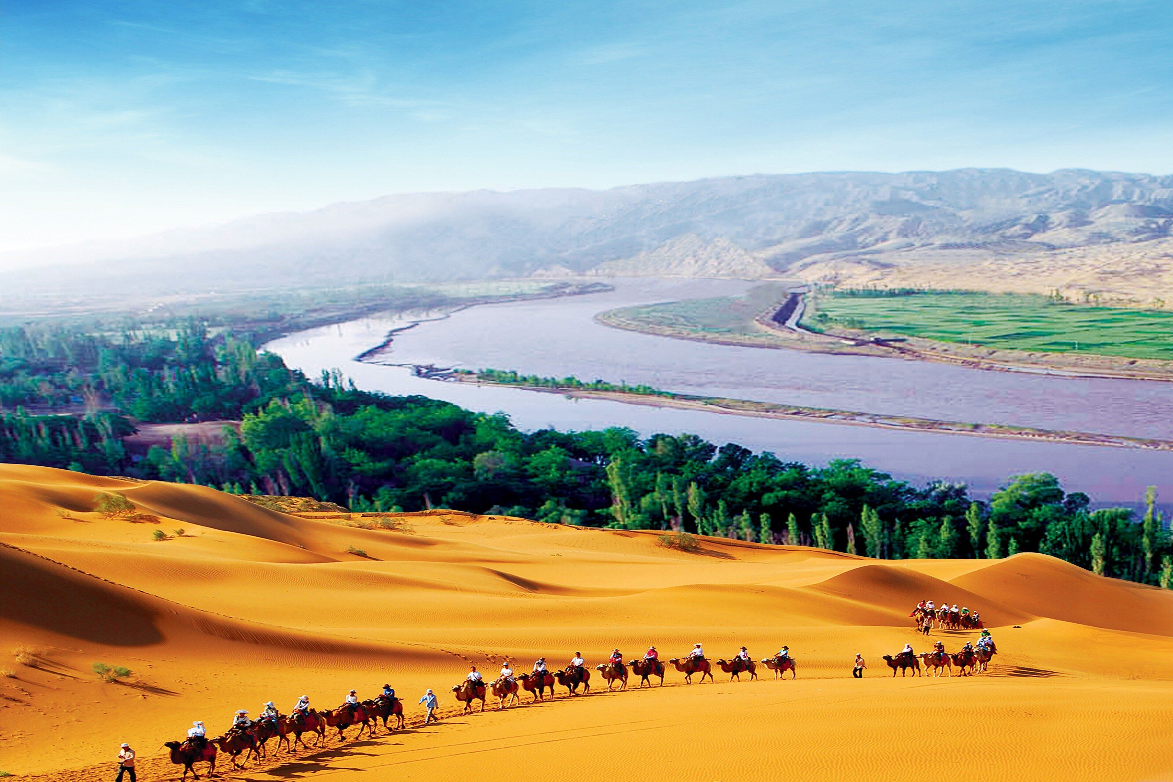 A desert landscape with sand dunes and a river.