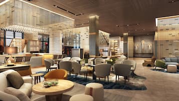 Un moderno vestíbulo de hotel con una zona de estar central, un bar y una escalera.