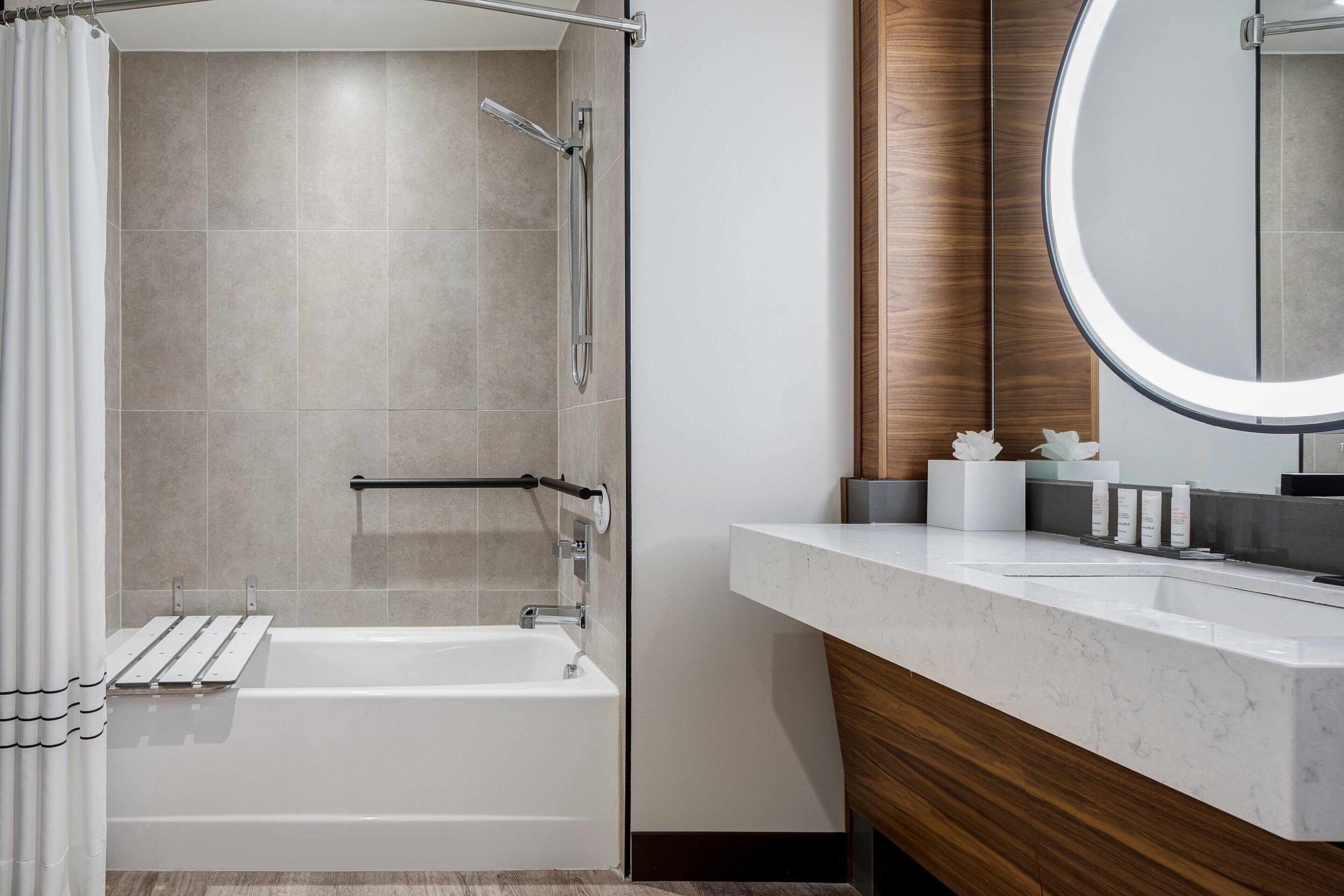 A modern bathroom with a bathtub, shower, and vanity with a mirror.