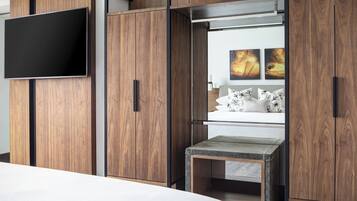 Un dormitorio moderno con una cama, un televisor montado en un mueble de madera y una pequeña mesa con un banco.