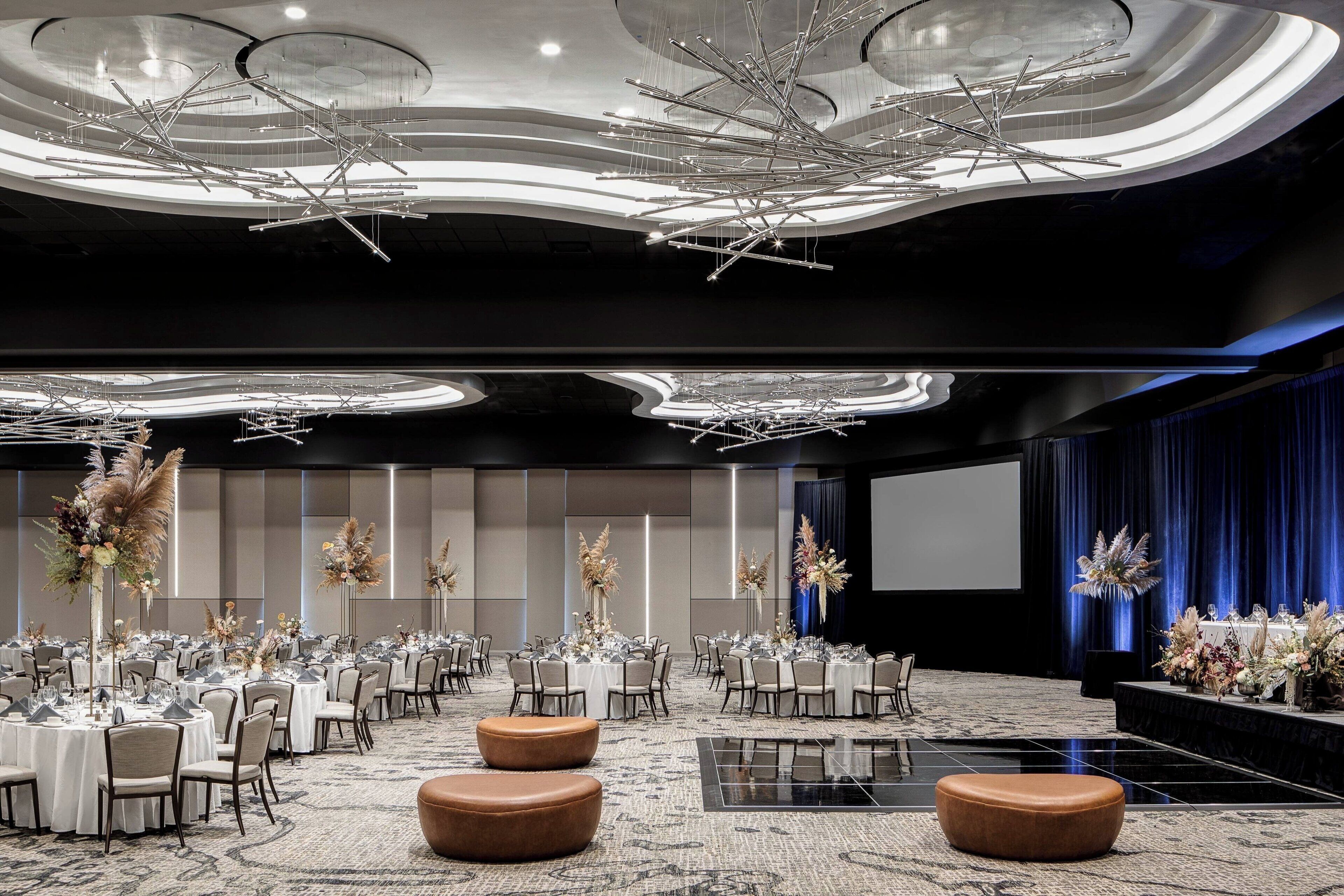 A spacious conference room with round tables, chairs, and a large screen.