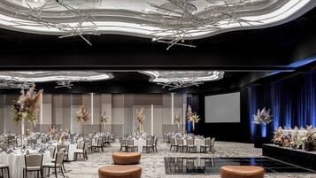 A spacious conference room with round tables, chairs, and a large screen.