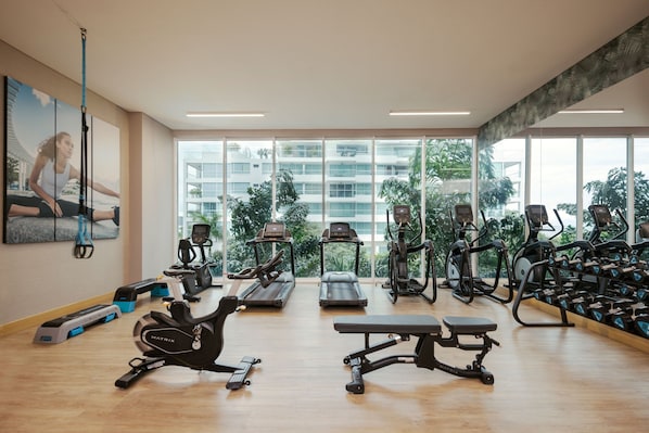 Un gimnasio con cintas de correr, elípticas y pesas sueltas.
