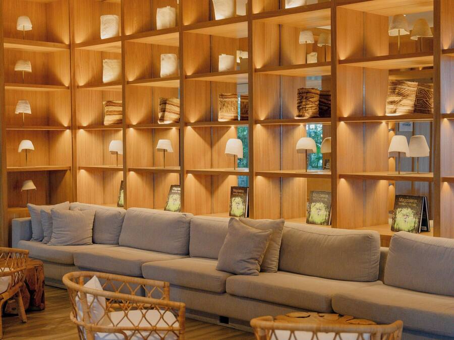 A modern living room with a wooden bookshelf, a grey sofa, and two wicker chairs.