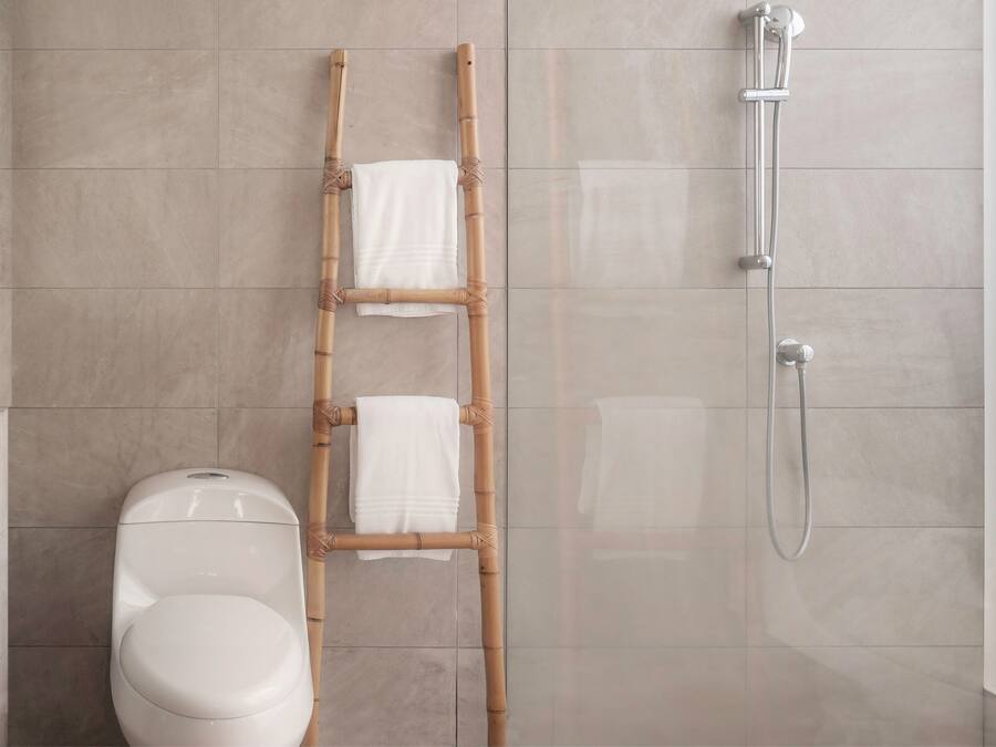 Baño con inodoro, escalera de bambú y ducha.
