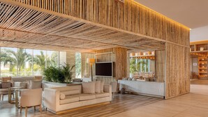 A spacious lobby with a wooden ceiling, a sofa, chairs, and a TV.