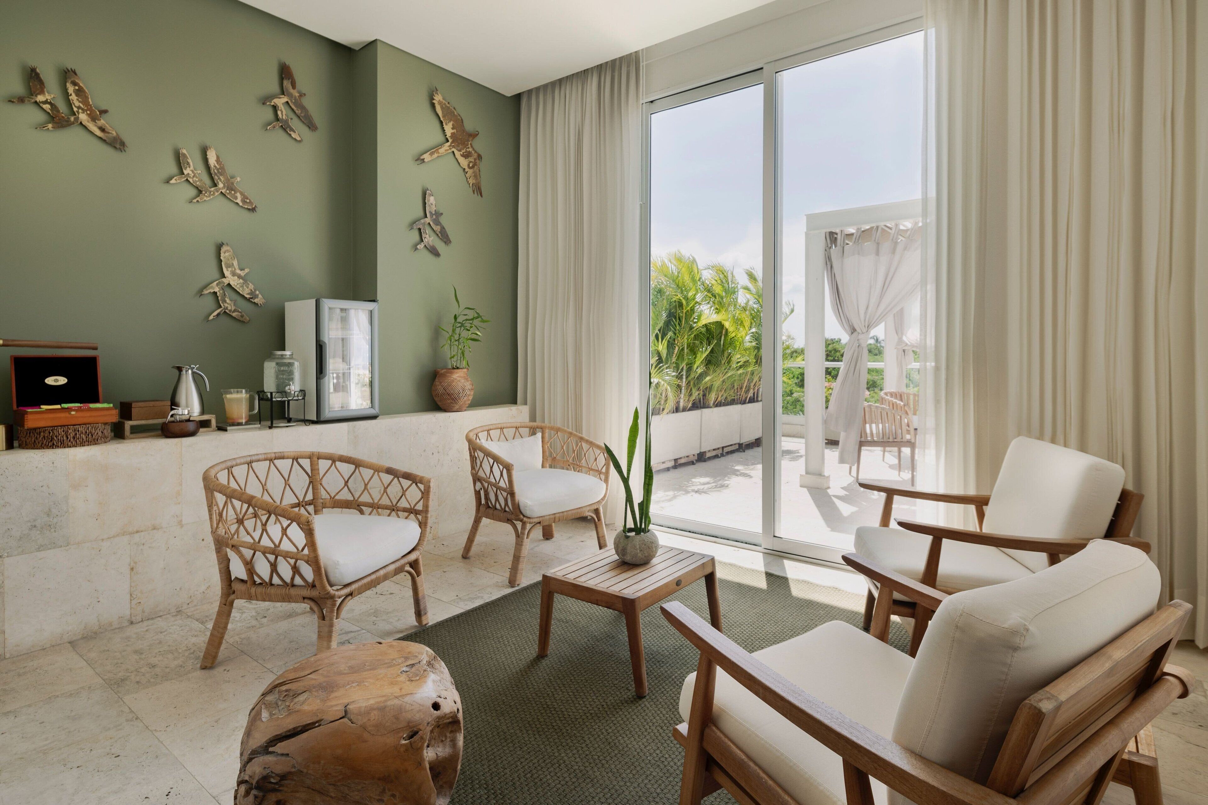 Un espacio habitable amplio con muebles de mimbre, un gran ventanal con cortinas y decoración en la pared.