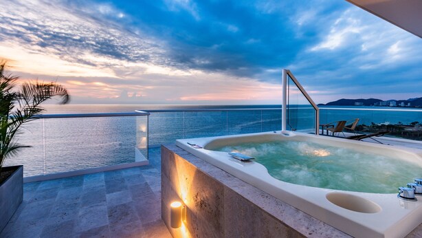 A hot tub on a balcony with a view of the sea and mountains.