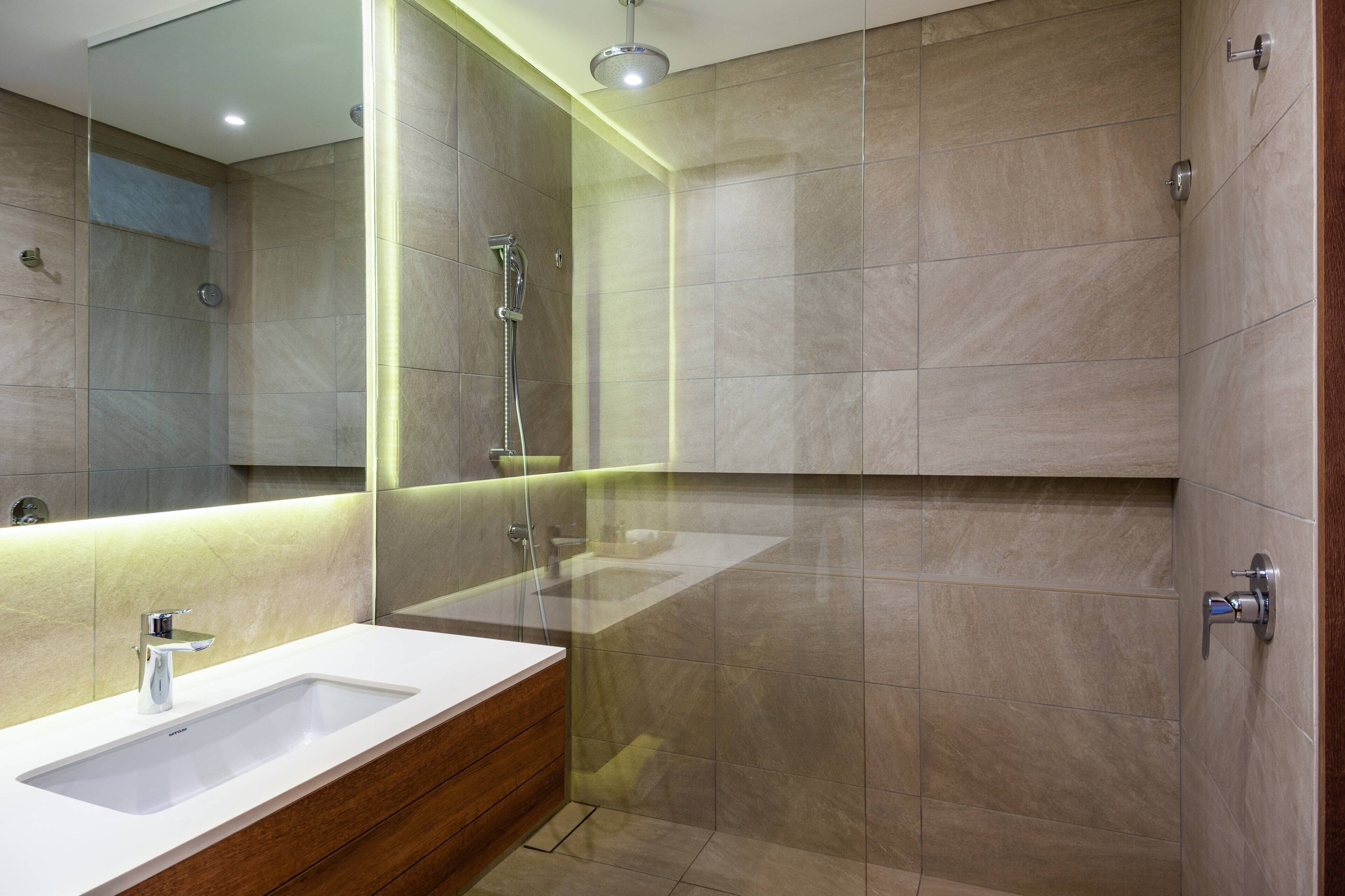 A modern bathroom with a large mirror, a sink, and a shower area.