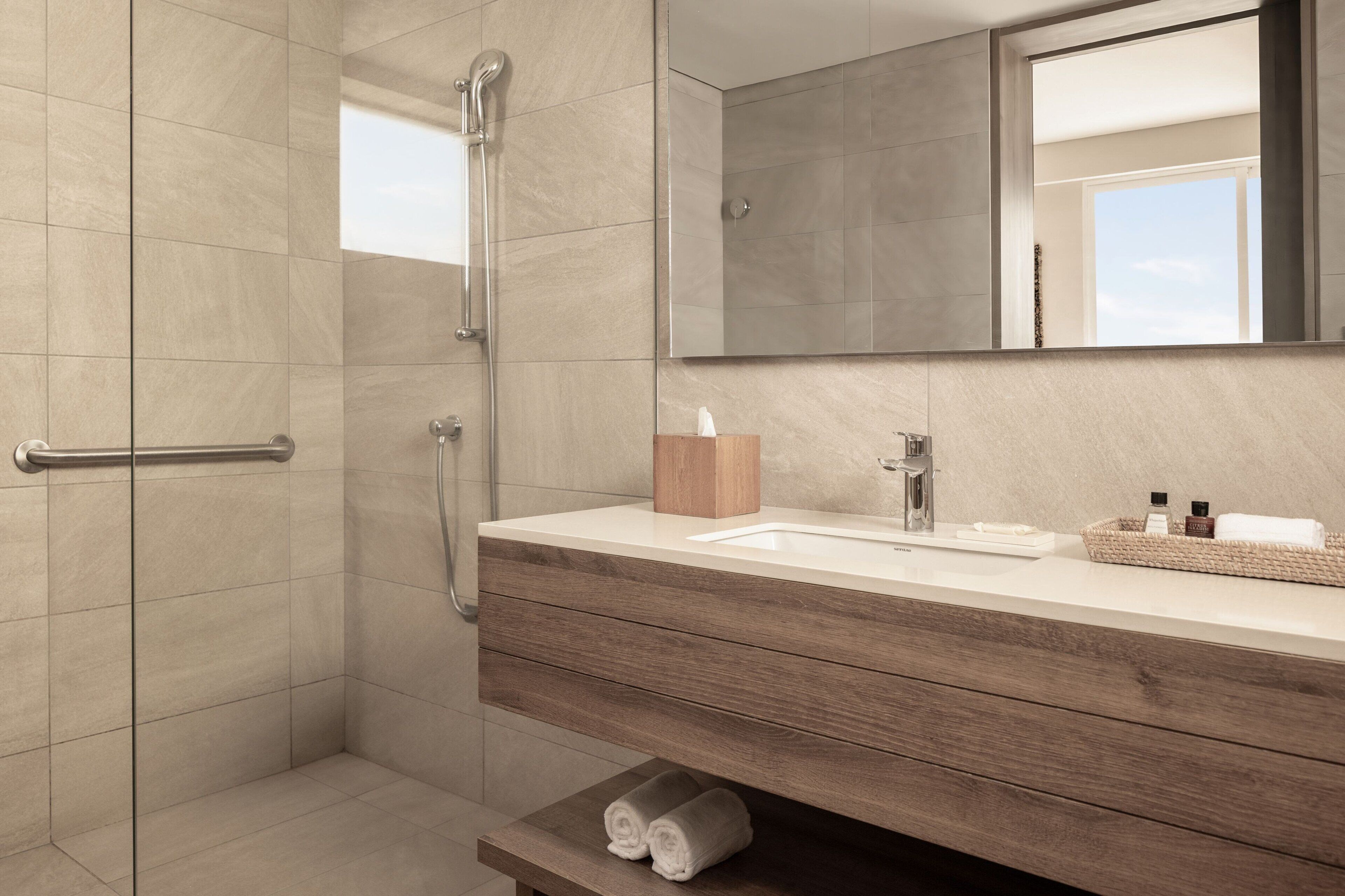 A modern bathroom with a walk-in shower, a vanity with a mirror, and a towel rack.