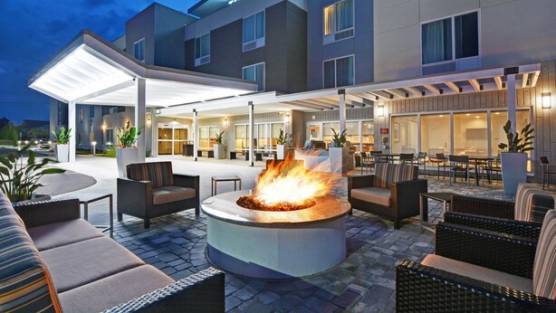 Exterior de un hotel con una zona de estar al aire libre cubierta, una chimenea y un letrero que dice "Townhouse Suites Marriott".