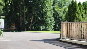 A paved driveway leading to a wooden fence with a birdhouse on the left.