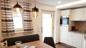 A modern kitchen with white cabinets, a built-in oven, and a coffee machine.