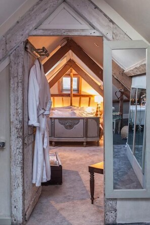 A bedroom with a sloped ceiling, a bed, a bedside table, and a window. - Westcroft Guesthouse (Torpoint)