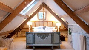 Een knus slaapkamer onder het dak met een vintage dressoir, een radiator en een dakraam.