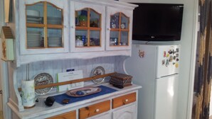 Une cuisine avec des meubles en bois, un réfrigérateur et un téléviseur.