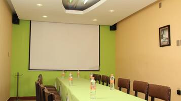 A conference room with a long table, chairs, a projector screen, and water bottles.