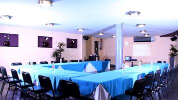 Una sala de conferencias con una larga mesa, sillas negras y una pantalla para proyector.