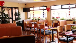 A restaurant with wooden tables and chairs, a large plant, and heart-shaped decorations. - Hotel Villa las Rosas (Tepic)