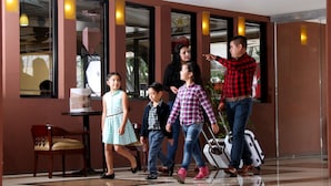 A group of people walking towards a building entrance, with a table and chair visible inside. - Hotel Villa las Rosas (Tepic)