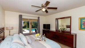 A bedroom with a bed, a ceiling fan, a TV, a dresser, a mirror, and a window with curtains. - Ellen`s House-pool and Jacuzzi, Gulf access (Cape Coral)