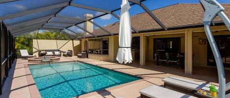 An outdoor swimming pool with lounge chairs and a covered seating area.