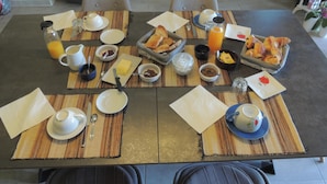 A breakfast table set with various dishes, including bread, pastries, and beverages, in a modern hotel room. - Les Chataigniers (Saint-Sebastien-d'Aigrefeuille)