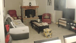 A living room with a fireplace, a sofa, a red armchair, a television, and a coffee table. - Les Chataigniers (Saint-Sebastien-d'Aigrefeuille)