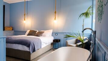 A bedroom with a bed, a bathtub, and a nightstand.