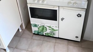 Een kleine keuken met een witte kookplaat, een oven en een klein aanrecht.