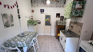 Een kleine keuken met een eettafel, een plafondventilator en een koelkast.