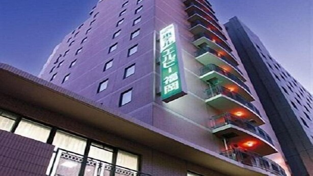 Een hoog gebouw met meerdere balkons en een groen bord waarop hotel staat.