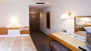 Een hotelkamer met een bed, nachtkastje, lamp en een spiegel.