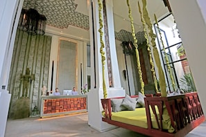A reception area with a reception desk, a seating area with a swing chair, and a statue. - Hari Residence & Spa (Siem Reap)
