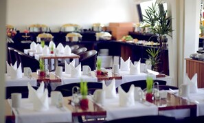 A restaurant with multiple tables set for dining, each with white napkins, glasses, and a centerpiece. - Hari Residence & Spa (Siem Reap)