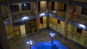 A multi-level atrium with glass railings, a blue seating area, and multiple balconies. - Regent Palace Hotel (Freetown)