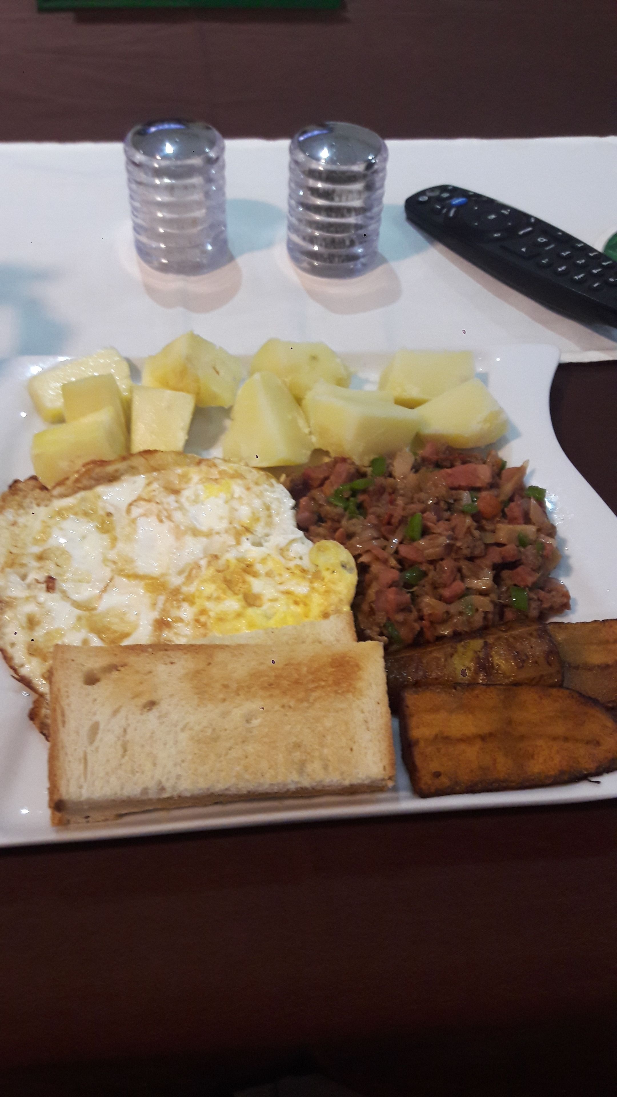 A breakfast plate with toast, eggs, potatoes, and a fried dish.